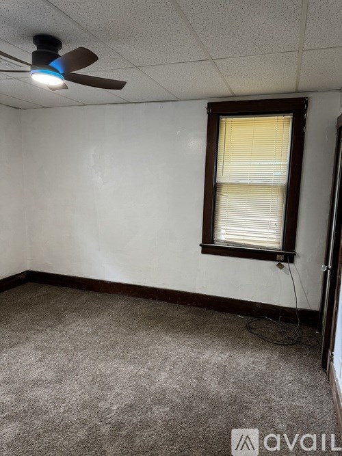 A room with a ceiling fan and a window with blinds.