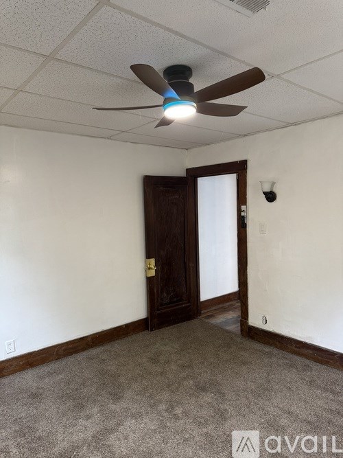 A room with a ceiling fan and a door.