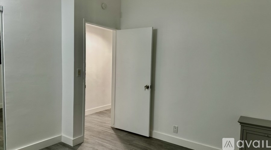 A room with a white door and a grey wall.