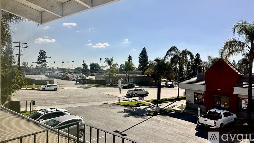 A parking lot with cars and a building with a sign that says "avail" in the foreground.