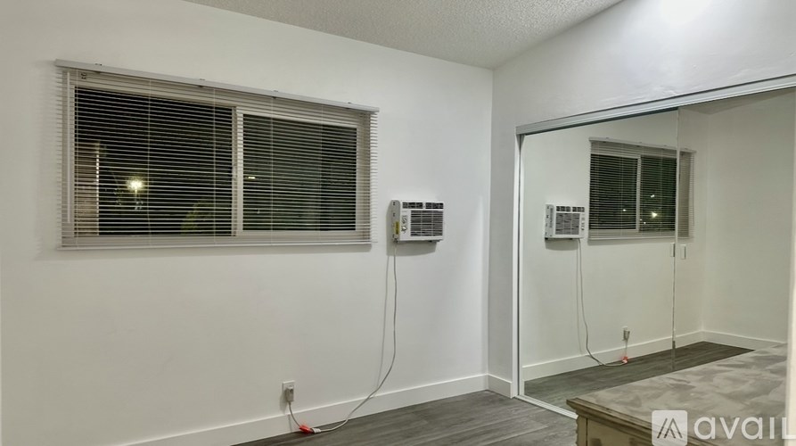 A room with a window, a mirror, and a wall-mounted air conditioner unit.