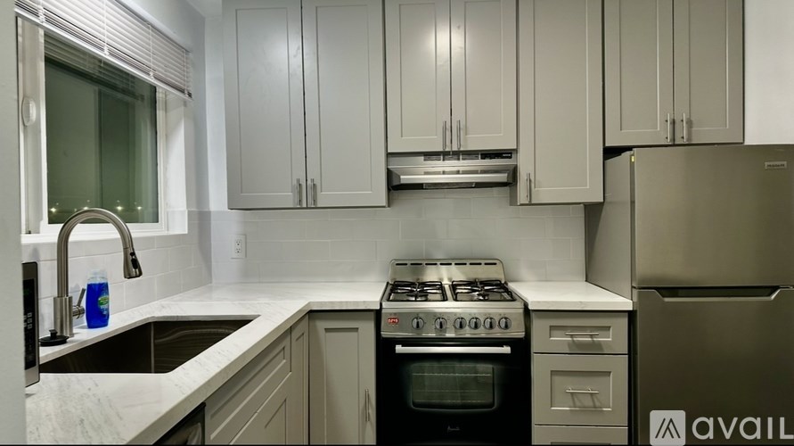 A kitchen with a stove, sink, and cabinets.