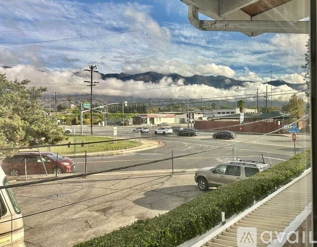 A view of a street with cars and mountains in the background.