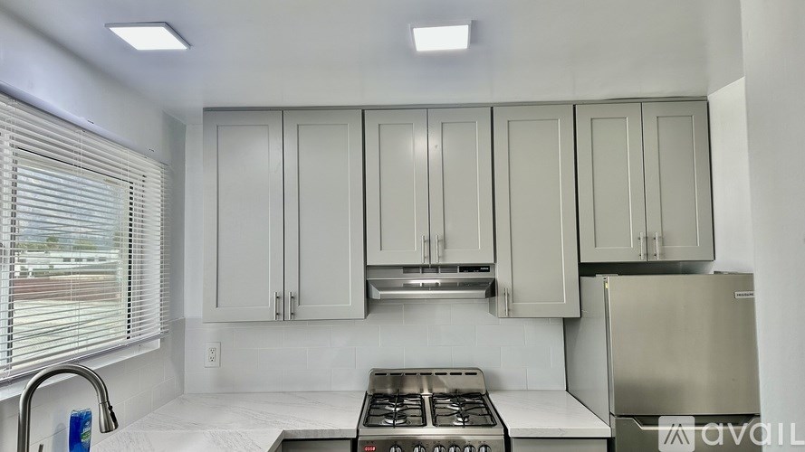 A kitchen with white cabinets and a stainless steel refrigerator.