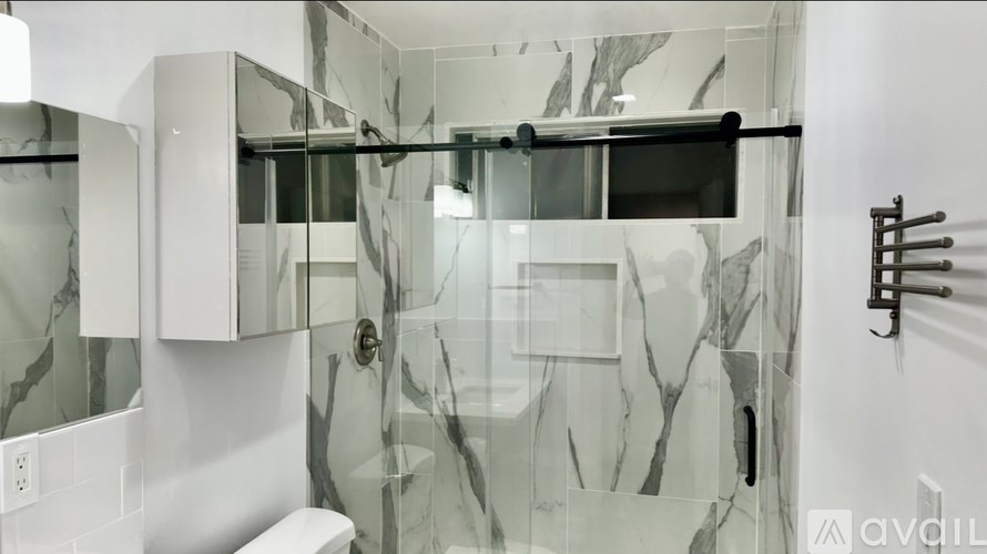 A bathroom with a marble patterned shower stall.