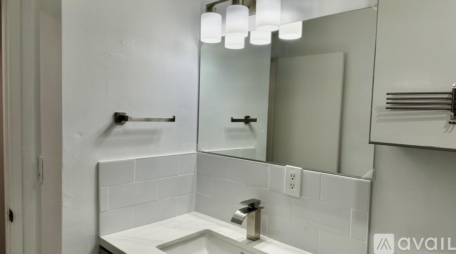 A bathroom with a white tiled wall and a white sink.