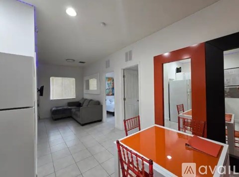 A kitchen with a white fridge, a table with chairs, and a sofa.