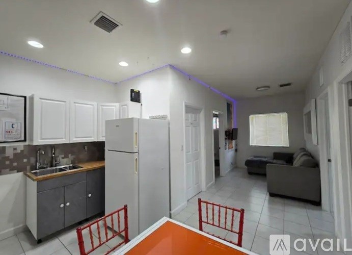 A kitchen with a refrigerator, sink, and cabinets.