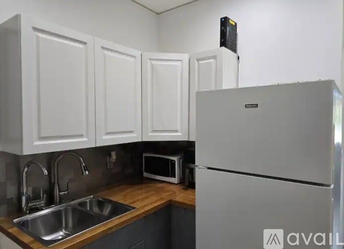 A kitchen with a refrigerator, sink, and microwave.