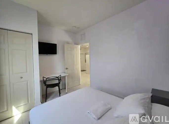 A bedroom with a bed, a chair, and a television.