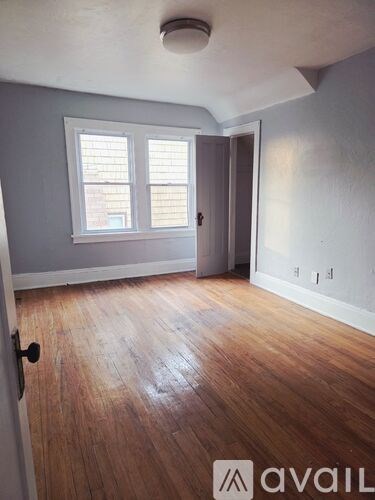 A room with wooden floors and a window with blinds.