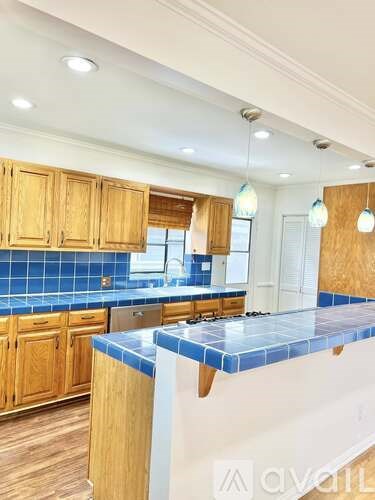 A kitchen with wooden cabinets and a blue tile backsplash.