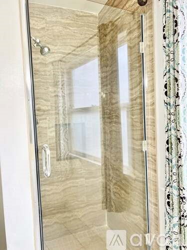 A shower with a glass door and a silver handle.