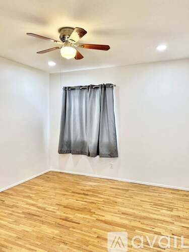 A room with a ceiling fan and a window with curtains.