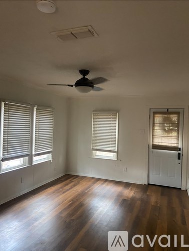 A room with a ceiling fan and wooden floors.
