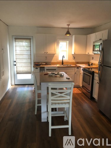 A kitchen with white cabinets and a wooden floor.