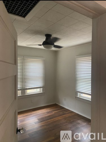 A room with a ceiling fan and wooden floors.