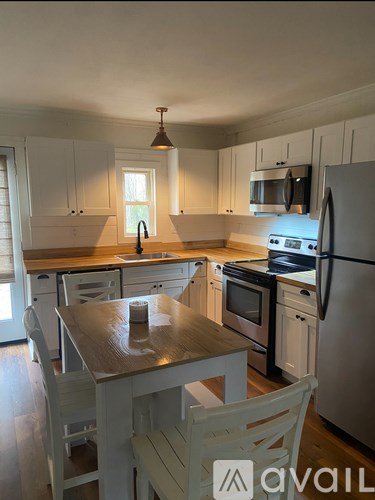 A kitchen with white cabinets and a wooden table.