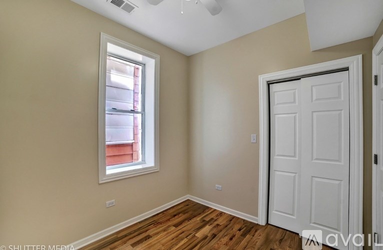 A room with a white door and a window with a view of a building outside.