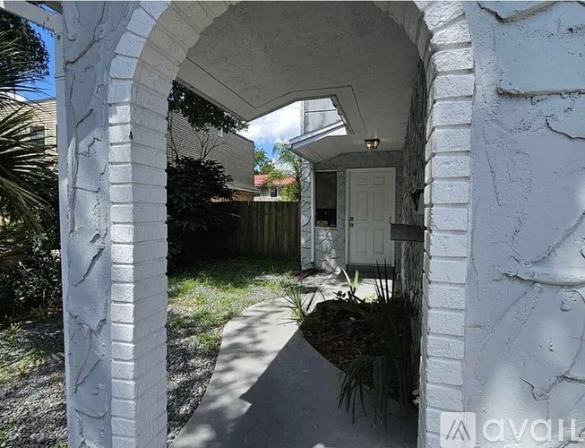 A white archway leads to a backyard with a fence and a door.