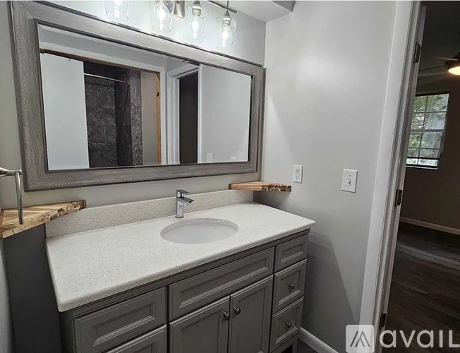 A bathroom with a sink, mirror, and cabinets.