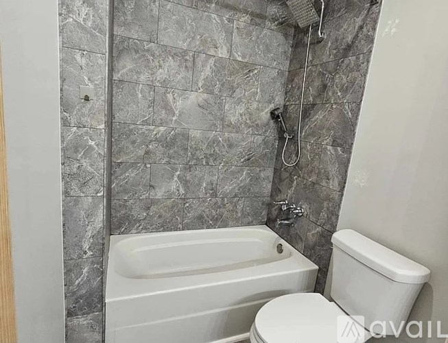 A bathroom with a bathtub, toilet, and tiled walls.