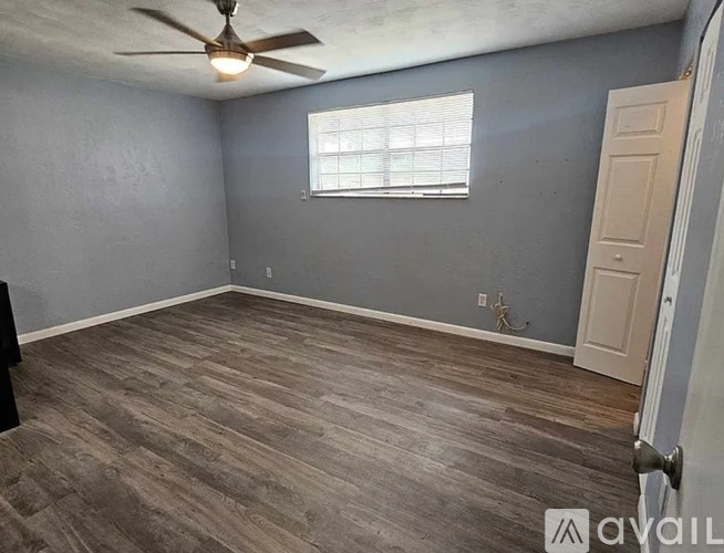 A room with a ceiling fan and a window with blinds.