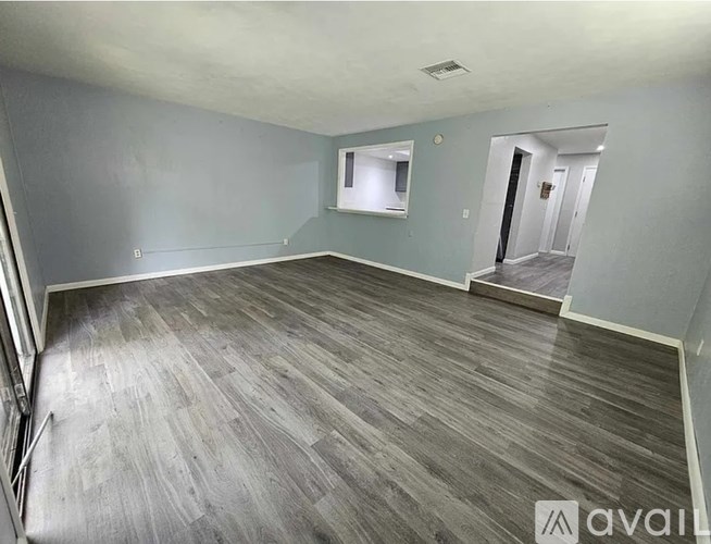 A spacious room with wooden flooring and a window.