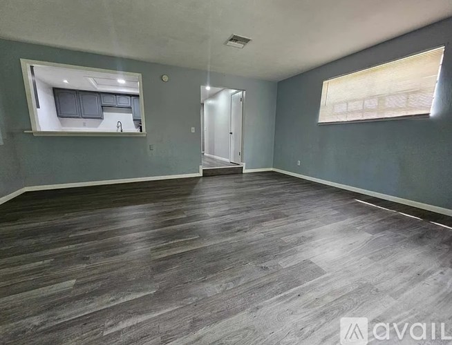 A spacious room with grey flooring and a window.