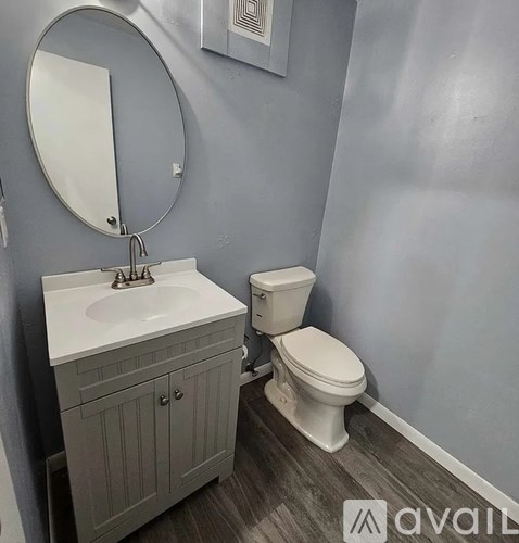 A bathroom with a toilet, sink, and mirror.