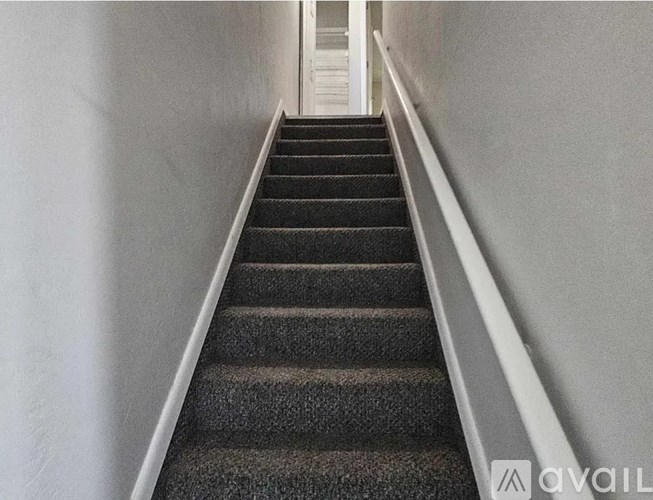 A staircase with a carpeted runner and white walls.