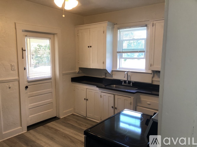 A kitchen with white cabinets and a black countertop.