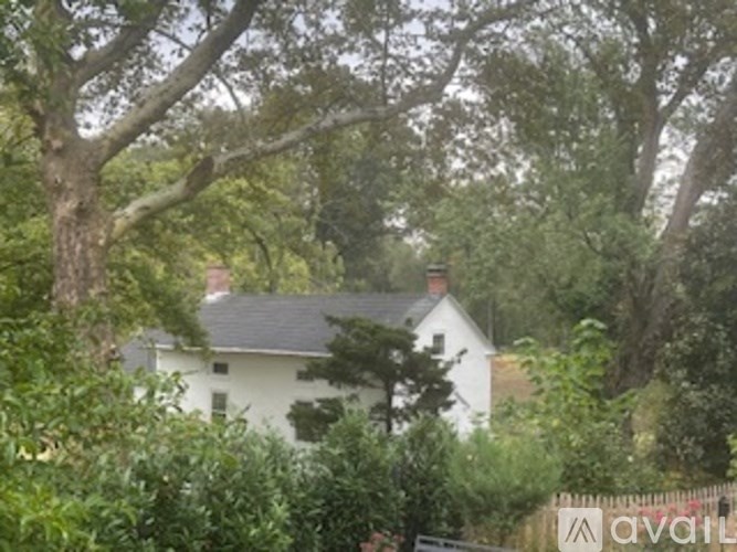 A white house is surrounded by trees and bushes.