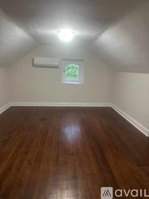 A room with wooden flooring and a window with a white frame.