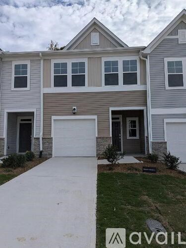 A two-story house with a garage and a driveway in front.