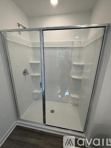A glass shower stall with a door and a handle.