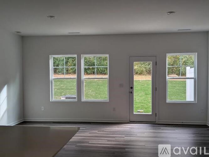 A room with a large window and a door leading to a grassy area.