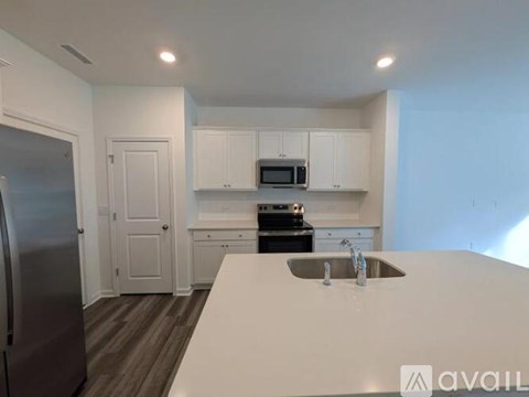 A kitchen with white cabinets and a stainless steel refrigerator.