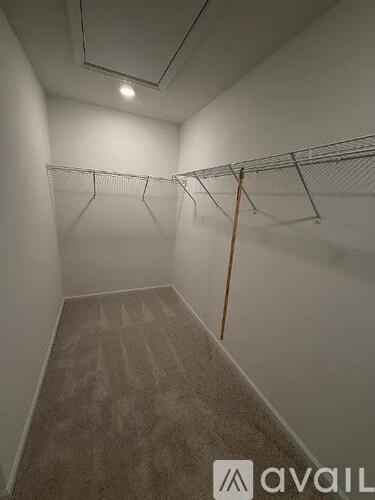 A room with a carpeted floor and a coat rack.