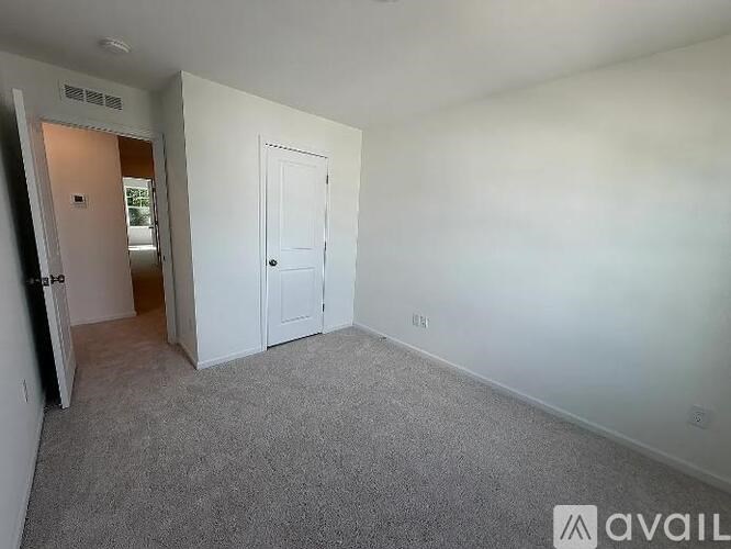 A room with a carpeted floor and two doors, one of which is open.