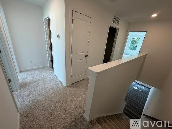 A room with a carpeted floor, a door, and a window with blinds.