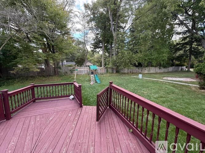 A wooden deck with a railing and a view of a backyard.