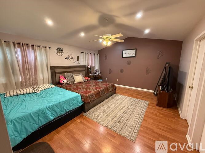 A bedroom with a bed, a ceiling fan, and a rug on the floor.