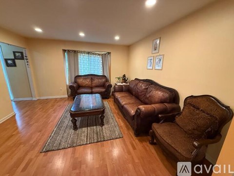 A living room with brown leather furniture and a rug.
