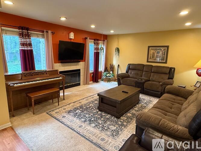 A living room with a piano, a fireplace, and a TV.
