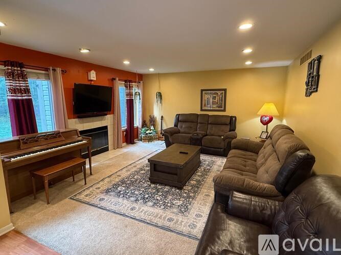 A living room with a brown leather couch and a piano.