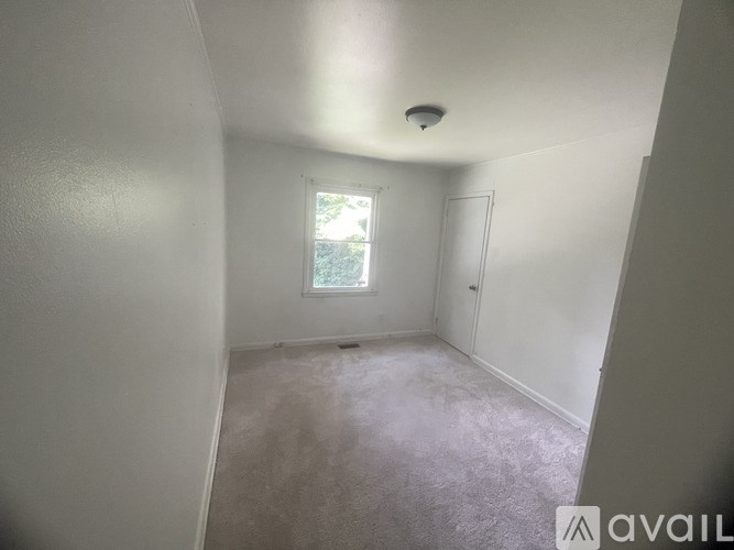 A room with a window and a door is available for rent.