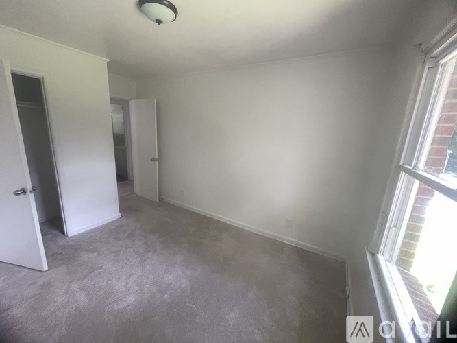 A room with a white door and a window with a view of a brick building outside.