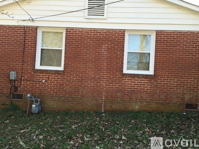 A red brick house with a white window and a white gutter.