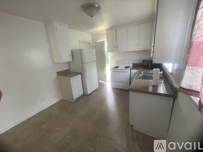 A kitchen with white cabinets and appliances is available for rent.